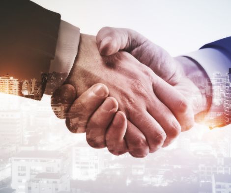 Two hands coming into a hand shake to show the importance of building partnerships when starting a social enterprise